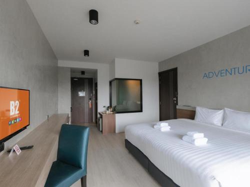 a hotel room with a large bed and a chair at B2 Krabi Premier Hotel in Ao Nang Beach