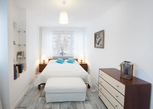 ein weißes Schlafzimmer mit einem Bett und einem Stuhl in der Unterkunft visit baltic - Matejki in Świnoujście