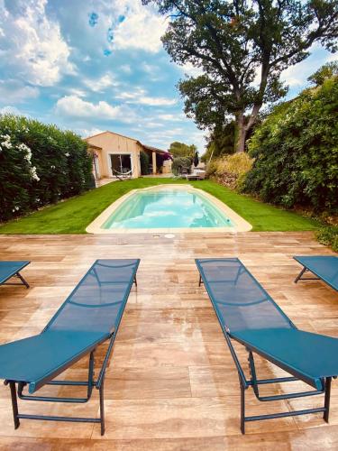 une piscine avec deux chaises longues bleues sur un patio dans l'établissement Villa 9 people maximum, à Bagnols-en-Forêt