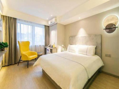 a hotel room with a bed and a yellow chair at Magnotel Fuzhou Wuyi Road Sanfangqixiang in Fuzhou