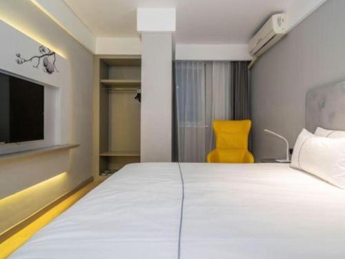 a bedroom with a large bed and a yellow chair at Magnotel Fuzhou Wuyi Road Sanfangqixiang in Fuzhou