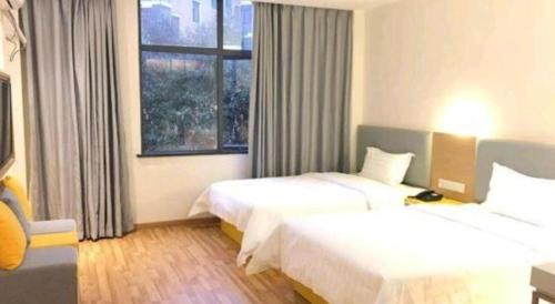 a hotel room with two beds and a window at 7 Days Inn·Ulanqab Tsining railway station in Ulanqab