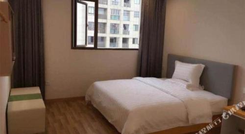 a bedroom with a white bed and a window at 7 Days Inn·Ulanqab Tsining railway station in Ulanqab
