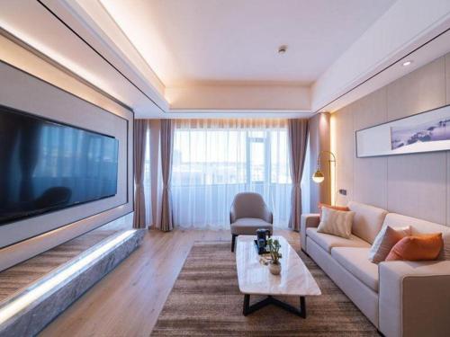 a living room with a couch and a large flat screen tv at GreenTree Eastern Dali Railway Station Hotel in Dali