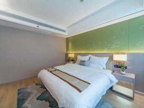 a bedroom with a large bed and a green wall at GreenTree Eastern Dali Railway Station Hotel in Dali