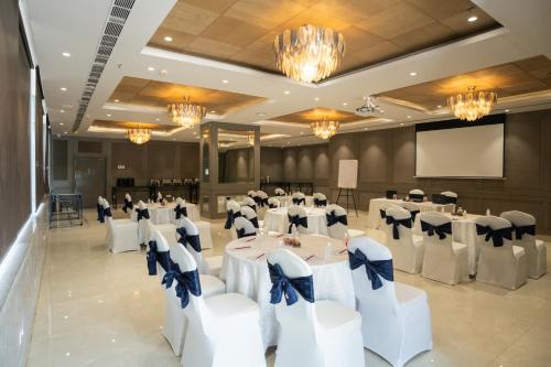 a banquet hall with white tables and chairs and a screen at AR Suites KLJ Square in Gurgaon