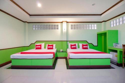 two beds in a room with green and red at OYO 75334 Train Hotel in Ban Don Rak