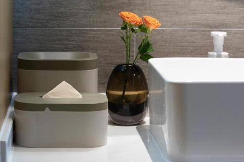 a vase with a flower in it next to a sink at Atour Hotel Weihai Shidao in Dongshan