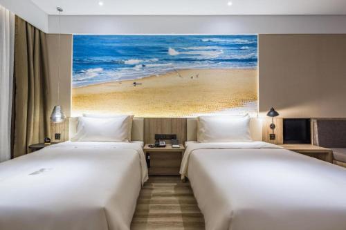 two beds in a hotel room with a painting of a beach at Atour Hotel Weihai Shidao in Dongshan