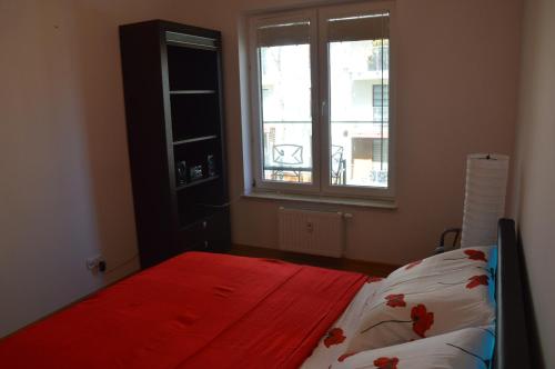 sypialnia z łóżkiem z czerwonym kocem i oknem w obiekcie Balticstars apartments polanki w Kołobrzegu