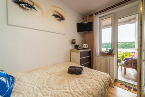 a bedroom with a bed and a window at Pokój z tarasem na jezioro, Mikołajki in Mikołajki
