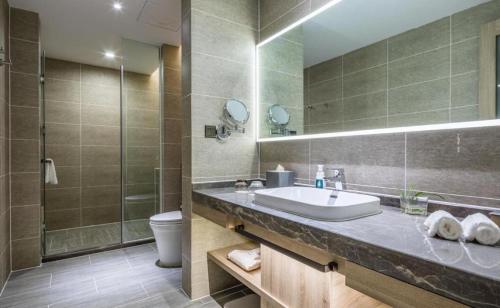 a bathroom with a sink and a toilet and a mirror at Atour Hotel Weihai Shidao in Dongshan
