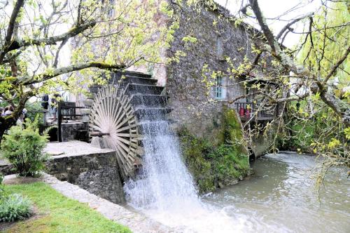 a waterfall next to a stone wall with a waterwheel at Gîte de vincés Lot-et-Garonne situé entre Bordeaux et Toulouse maison rurale, Maison en campagne in Tombeboeuf