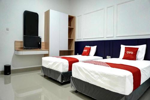 two beds with red pillows in a room at Capital O 92804 La Tansa Syariah Hotel in Bekasi