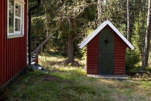 a red dog house with a door next to a house at Private Plan Torpet Cabin in Södra Ström
