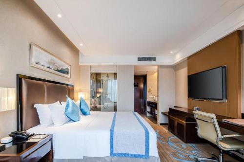 a hotel room with a bed and a flat screen tv at Chengdu Rising Butterfly Hotel in Chengdu