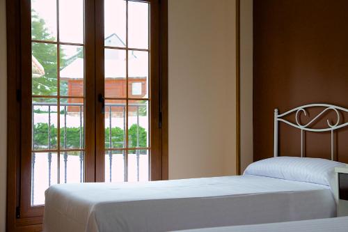 two beds in a room with a large window at Complejo Hotelero La Braña in San Isidro