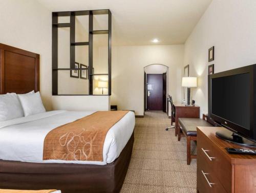 a hotel room with a bed and a flat screen tv at Comfort Suites near NASA - Clear Lake in Webster