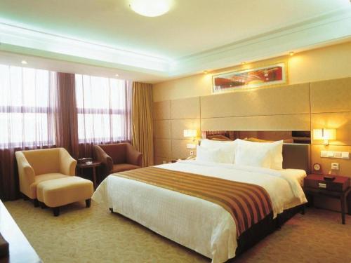 a hotel room with a large bed and a chair at Xian Union Alliance Atravis Executive Hotel in Xi'an