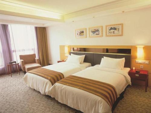 a hotel room with two beds and a chair at Xian Union Alliance Atravis Executive Hotel in Xi'an