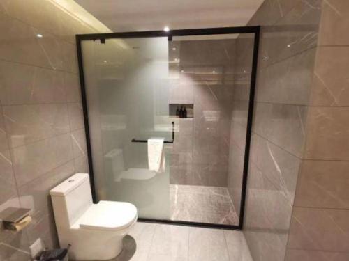 a bathroom with a toilet and a glass shower at Xian Union Alliance Atravis Executive Hotel in Xi'an