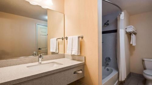 a bathroom with a sink and a toilet and a mirror at Best Western Plus Twin View Inn and Suites in Redding