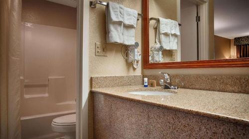 a bathroom with a sink and a toilet and a mirror at Best Western Windsor Inn in Dumas