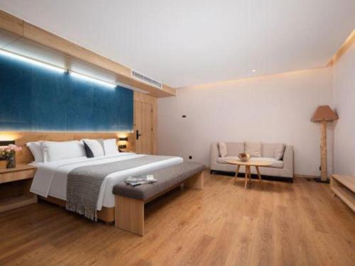 a large bedroom with a large bed and a couch at New Beacon Sunyee SPA Hotel in Wuhan