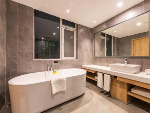 a bathroom with a large tub and a sink at New Beacon Sunyee SPA Hotel in Wuhan