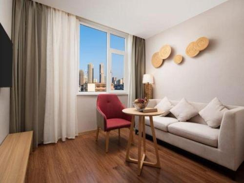 a living room with a couch and a table and a window at New Beacon Sunyee SPA Hotel in Wuhan
