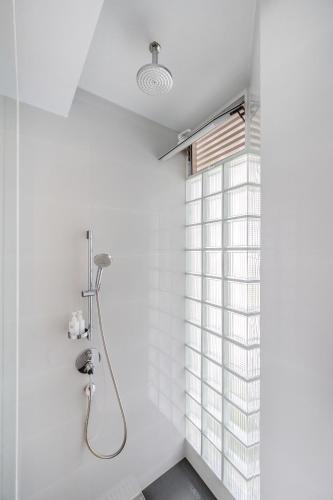 a white bathroom with a shower and a window at Pure Sunset Beach - Ocean View Room, Pattaya in Na Jomtien