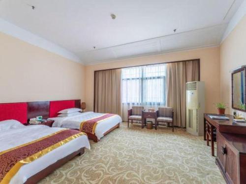 a hotel room with two beds and a desk at Jinggangshan Edenplaza Hotel in Jinggangshanzonghekenzhichang