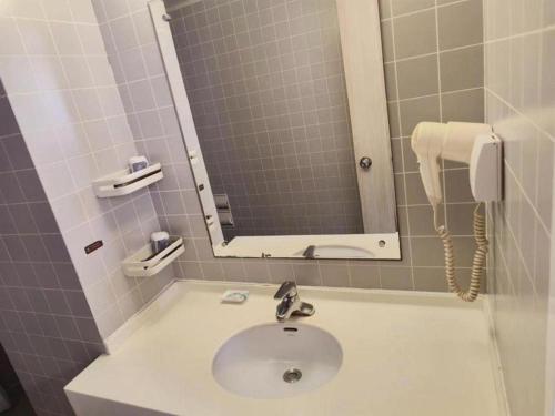 ein Badezimmer mit einem Waschbecken mit Spiegel und einem Telefon in der Unterkunft Jinjiang Inn Dalian Railway Station Russian Street in Dalian