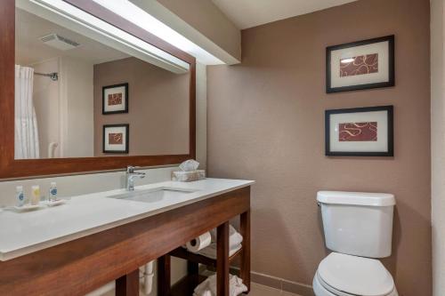 a bathroom with a sink and a toilet and a mirror at Comfort Suites Sawgrass in Tamarac