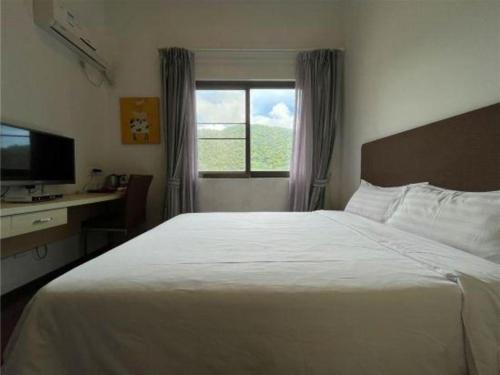 a bedroom with a large white bed and a window at The Century Seaview Hotel in Shenzhen