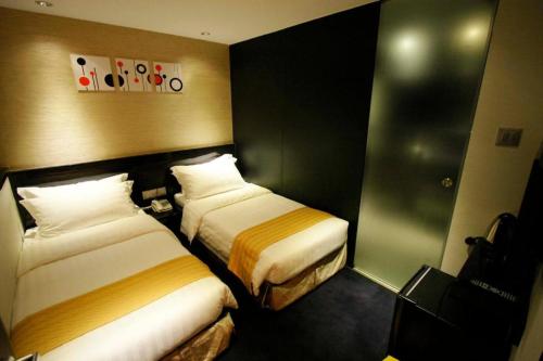 a hotel room with two beds in it at Noble Park Hotel in Hong Kong