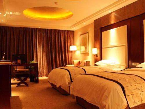 a hotel room with two beds and a desk at Northwest Petroleum Hotel in Ürümqi