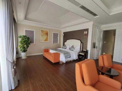 a bedroom with a bed and two orange chairs at The Century Seaview Hotel in Shenzhen