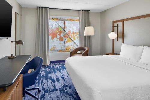 a hotel room with a bed and a desk and a window at Fairfield Inn by Marriott Rochester East in Webster