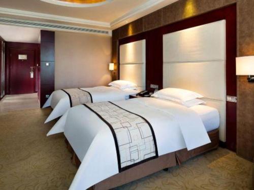 a hotel room with two beds in a room at Northwest Petroleum Hotel in Ürümqi