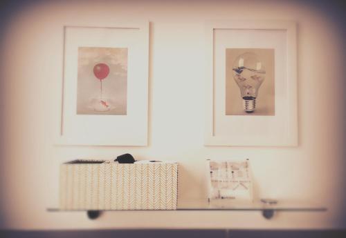 a shelf with three pictures on a white wall with paintings at Torrearsa 17 in Trapani
