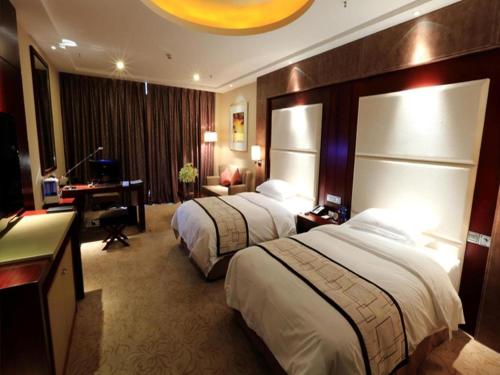 a hotel room with two beds and a desk at Northwest Petroleum Hotel in Ürümqi