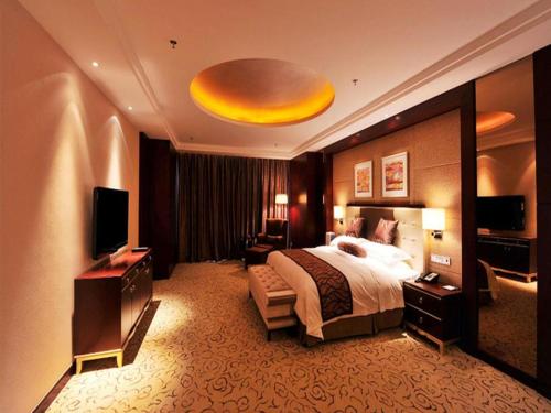 a hotel room with a bed and a television at Northwest Petroleum Hotel in Ürümqi