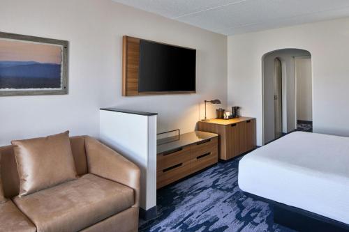 a hotel room with a bed and a couch and a television at Fairfield Inn by Marriott Rochester East in Webster