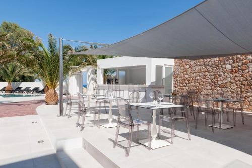 a patio with tables and chairs under an umbrella at MAR n MAR CROWN HOTEL-SUITES in Kamari