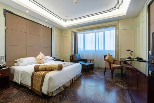 a hotel room with a large bed and a desk at Jiuhua Jin Jiang International Hotel in Zhenjiang