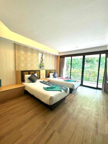 a bedroom with two beds and a large window at Phi Phi Nice Beach Hotel Hip in Phi Phi Don