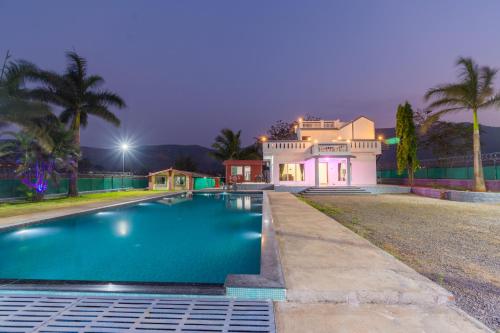 a large house with a swimming pool in front of it at Aaru Retreat - Lonavala in Khamshet