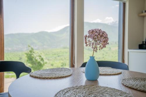 un tavolo con un vaso blu con un fiore all'interno di Almaty Hills VIP House a Almaty
