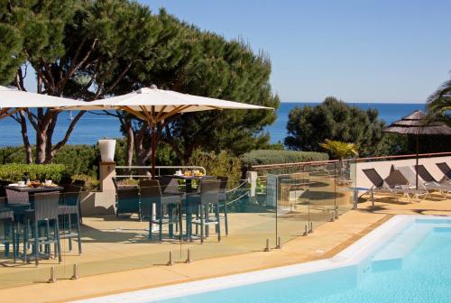 a pool with chairs and tables and umbrellas next to a swimming pool at Hôtel & Spa Les Mouettes in Argelès-sur-Mer
